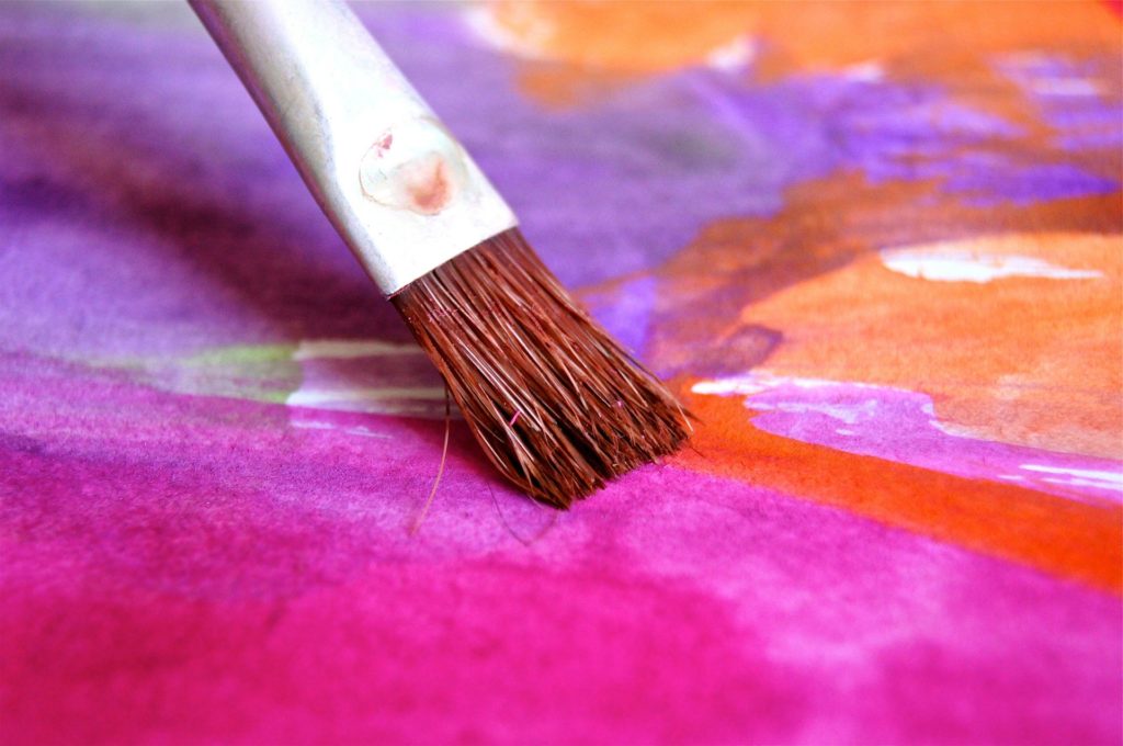 Pinsel auf violett-orange-weißem Bild - unsere kreativität finden wir im 5. Haus, im Löwe-Haus
