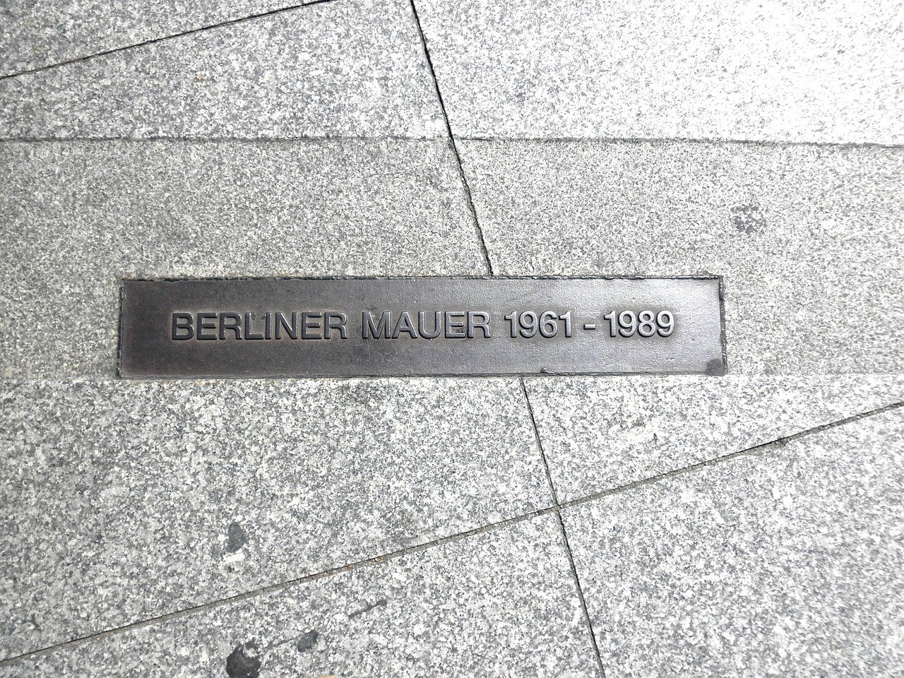 Gehwegplatten mit einer Metallplatte in der Mitte "Berliner Mauer 1961-1989"