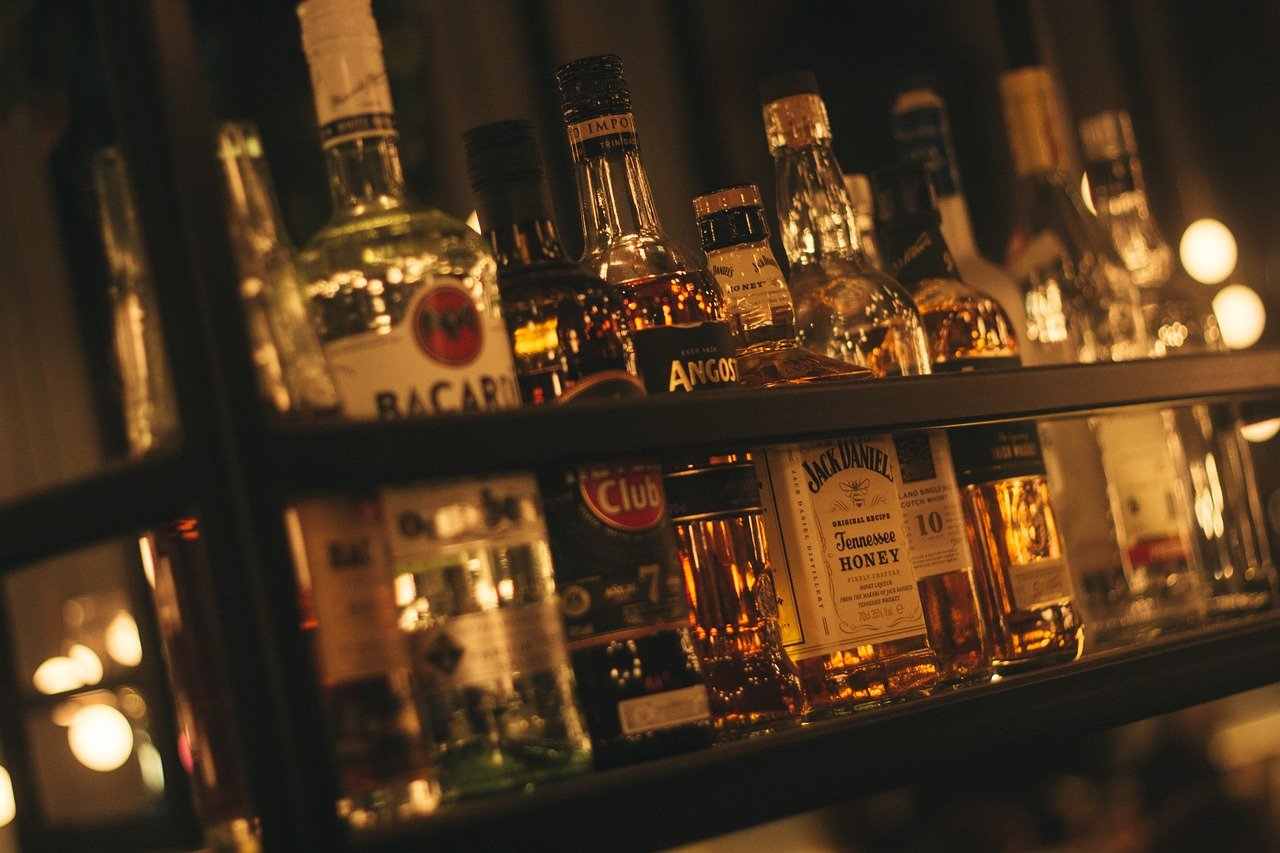 Alkohol in einer Bar, Flaschen von Bacardi, Rum, Jack Daniels aufgereiht - Jupiter-Neptun Konjunktion