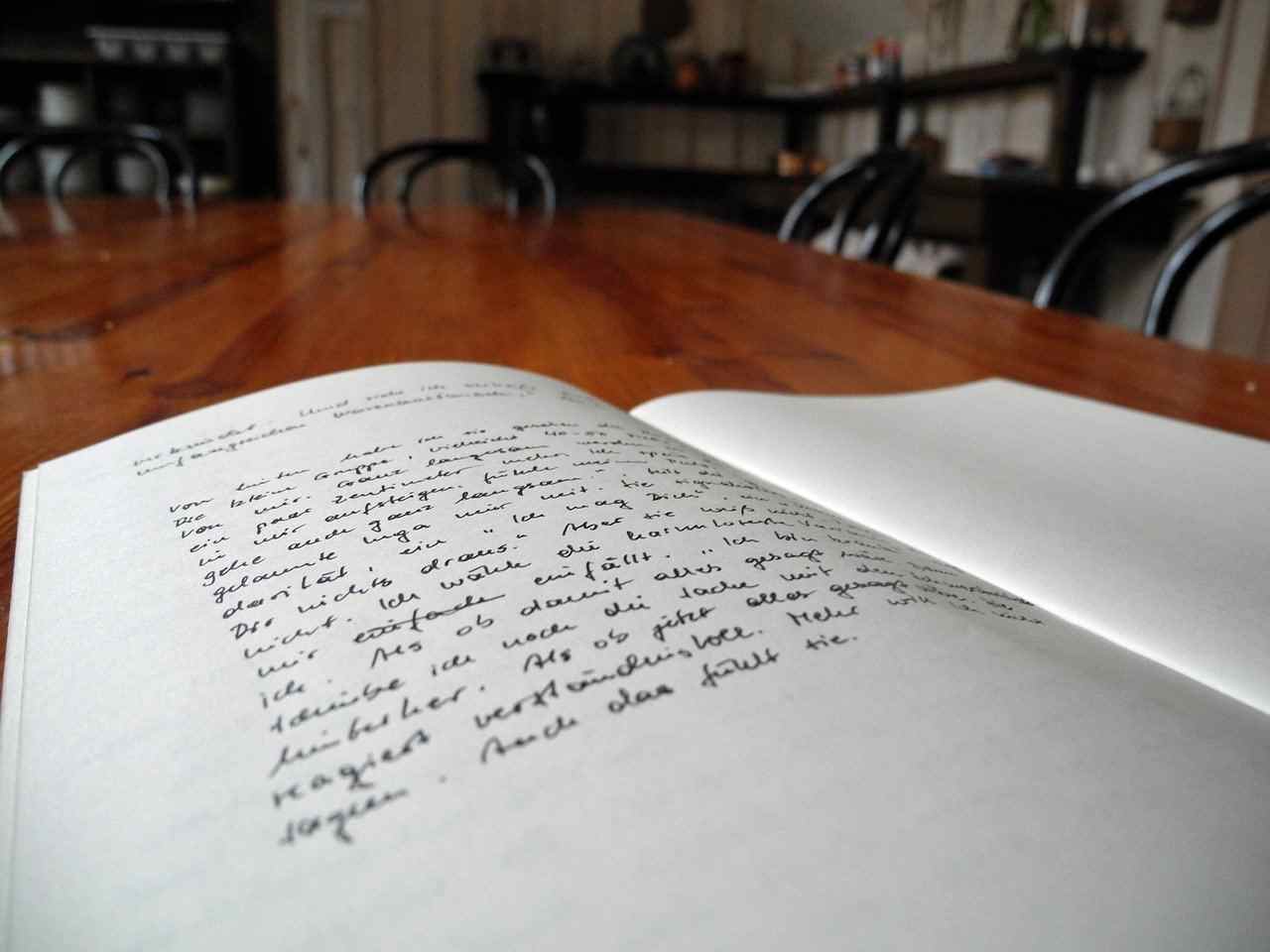 Kladde auf einem Tisch aufgeschlagen, die linke Seite in Handschrift beschrieben - Vollmond in Waage - eine neue Geschichte schreiben