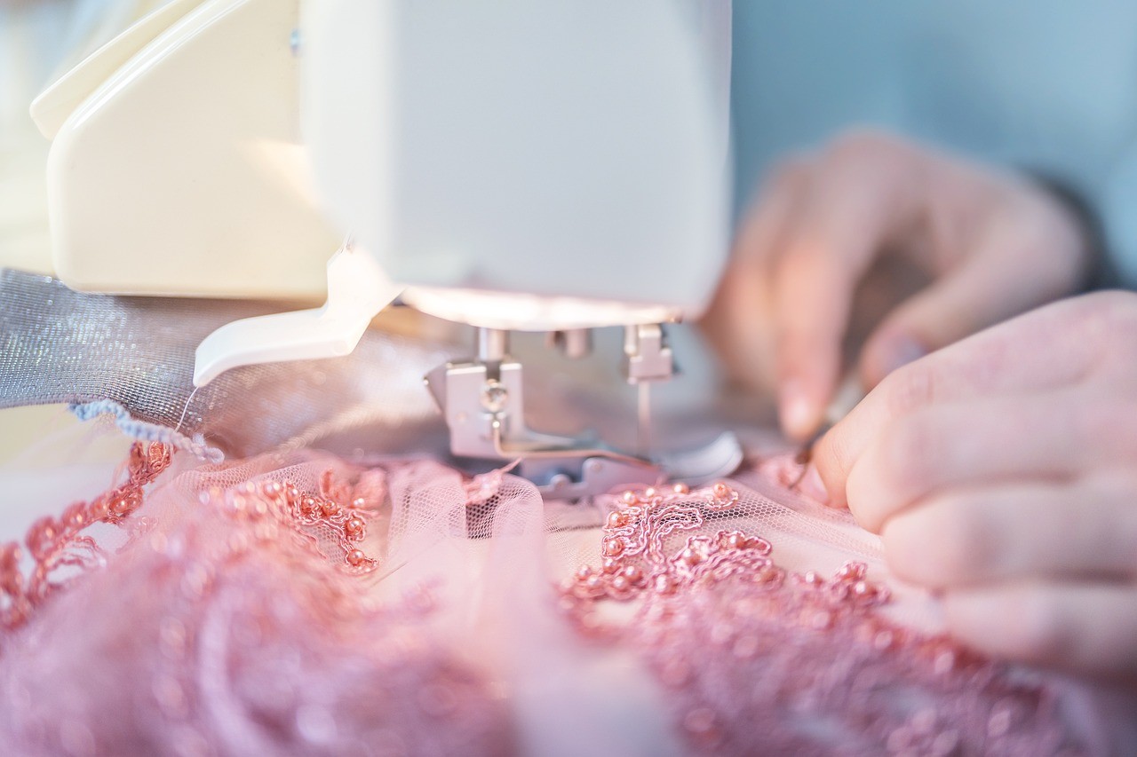 Bestickter Stoff mit Perlen unter der Nähmaschine - Erdzeitalter, Luftzeitalter 
