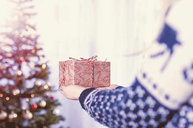Weihnachtsbaum im Hintergrund, Hand, die ein Geschenk gibt - warten auf die Jupiter Uranus Konjunktion wie auf Weihnachten