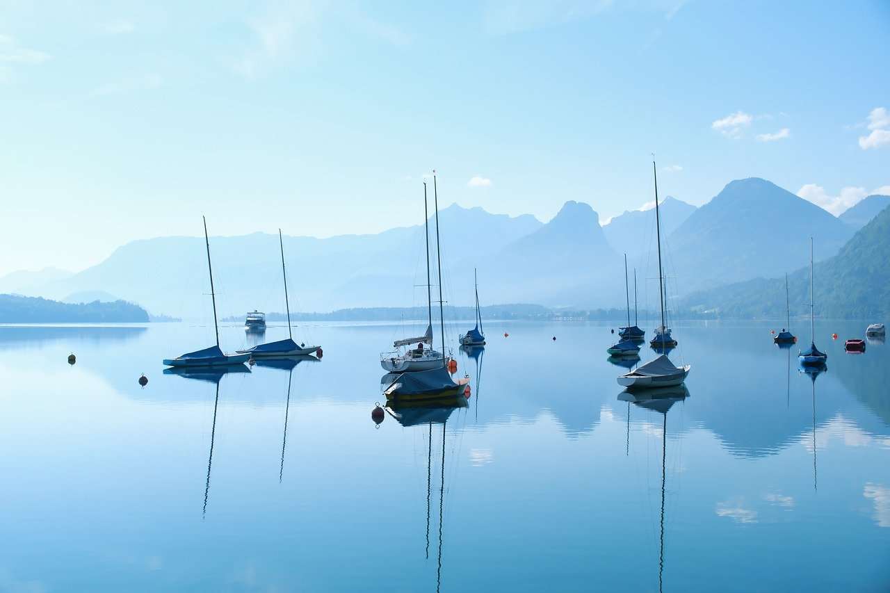Boote auf dem Wolfgangsee, glatte Wasseroberfläche, Stille und Berge im Hintergrund - Zeit der Stille und der Innenschau- Mars rückläufig